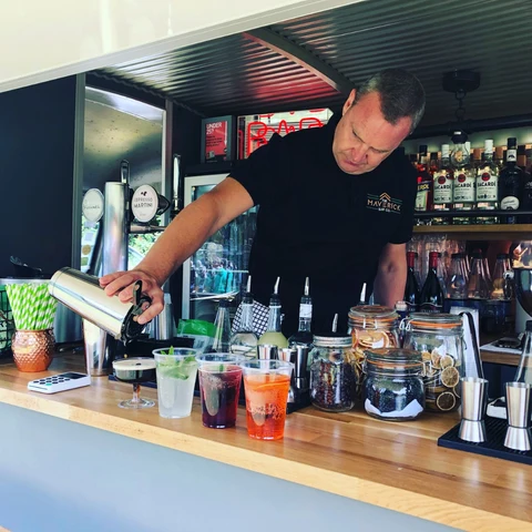 Mobile bartender pouring cocktails from a portable bar cart at an outdoor event